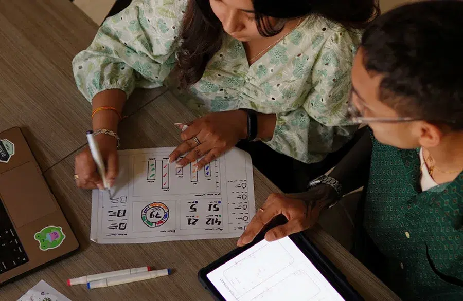 One employee on a tablet, another sketching on paper, bringing client ideas to life through prototypes and low-fidelity designs.