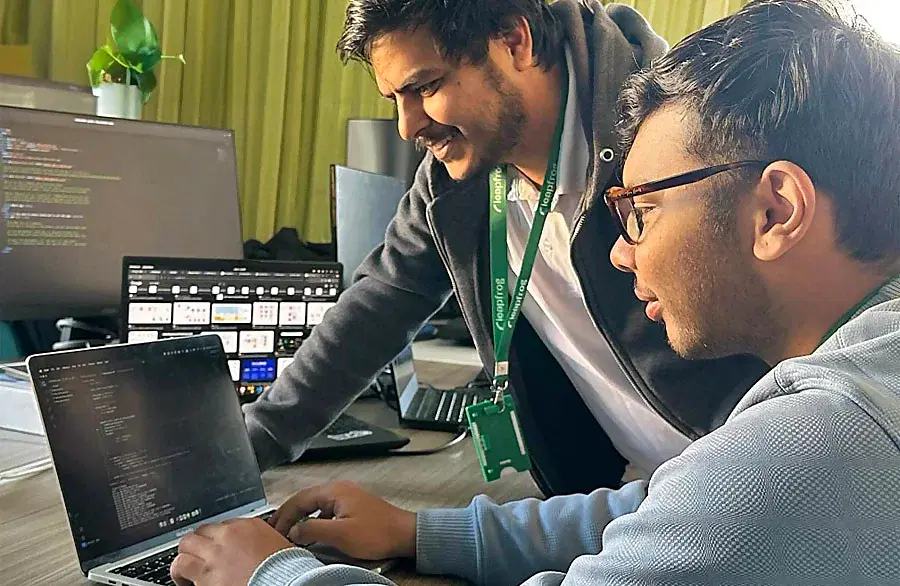 Three data engineers working together with two laptops on AI/ML solutions.