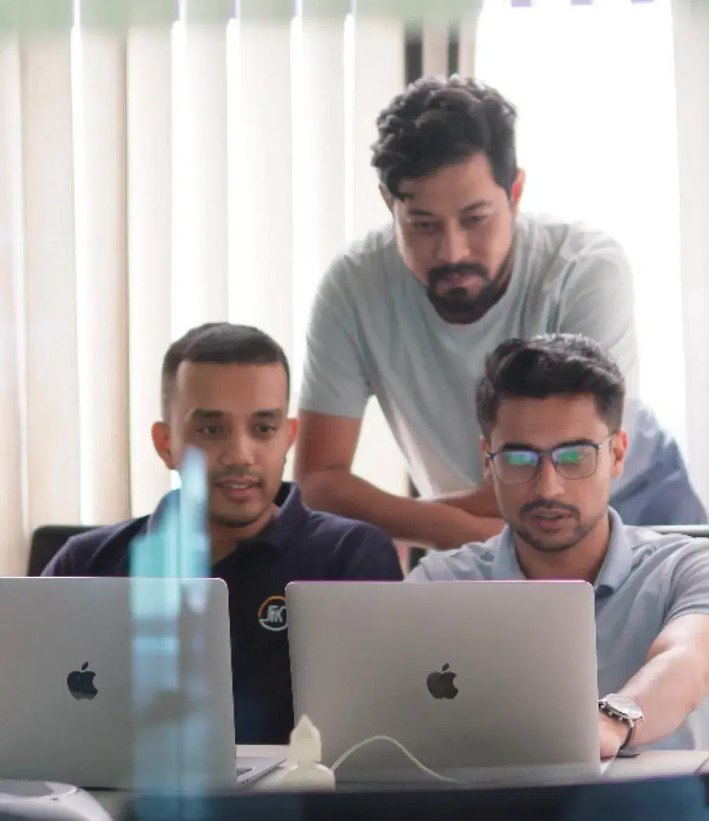 Three data engineers working together with two laptops on AI/ML solutions.